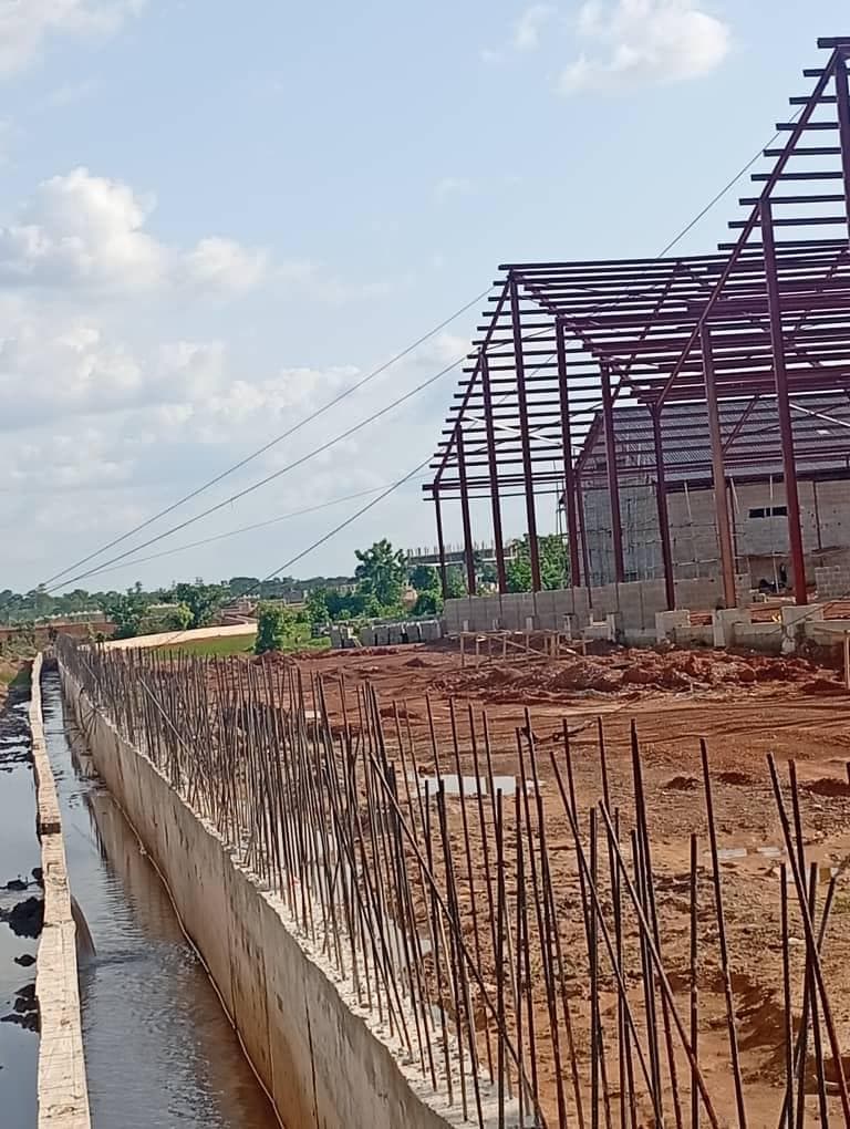 Concrete drainage channel with starter bars, and steel-frame buildings behind