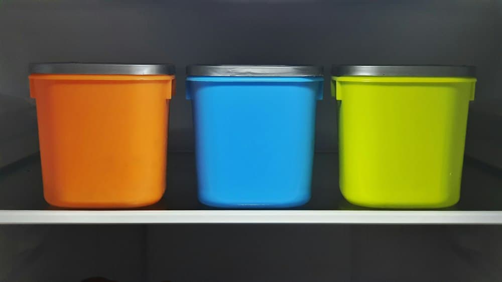 Orange, blue, and green plastic tubs on a shelf