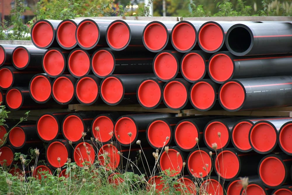 Stacked black plastic pipes with red end caps