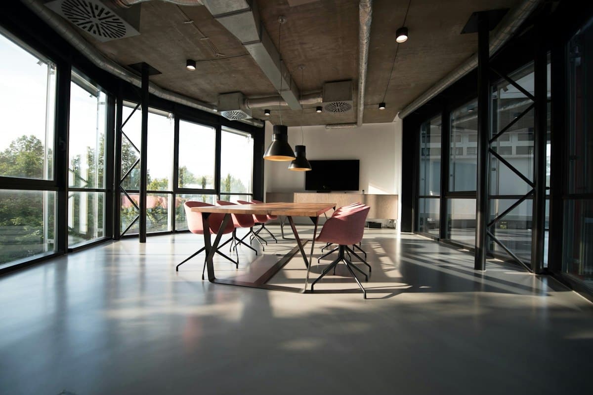 Open-plan office space with floor-to-ceiling windows and a meeting table