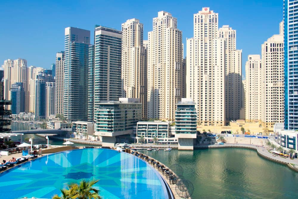 Dubai Marina towers rising behind a curved swimming pool